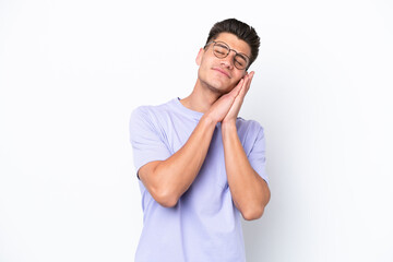 Young caucasian man isolated on white background making sleep gesture in dorable expression