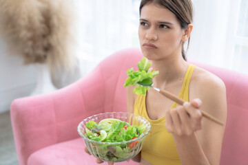 Unhappy young Caucasian woman does not want to eat vegetables and does not like the bitter taste of vegetables.