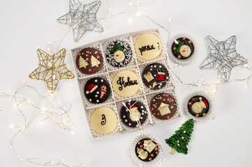 New Year's chocolates with symbols of New Year's holidays in a box, on a white background with stars and a garland and balls, the inscription in Ukrainian, Happy New Year
