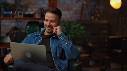 Businessman working from home on laptop computer. Happy young man sitting on couch in home office with laptop.