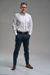 Full length business portrait of confident businessman. Entrepreneur in white shirt, smiling, Happy mid adult, mature age man standing, smiling, isolated on gray background.