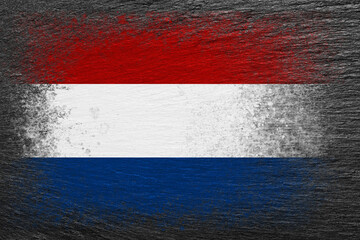 Flag of Netherlands. Flag is painted on black slate stone. Stone background. Copy space. Textured background