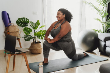 Young African woman taking Pilates fitness class with laptop at home - Sport wellness people...