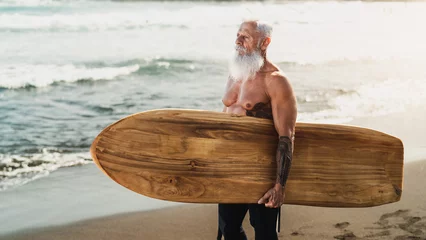 Fotobehang Senior fit man surfing on tropical beach - Elderly healthy people lifestyle and extreme sport concept © Alessandro Biascioli