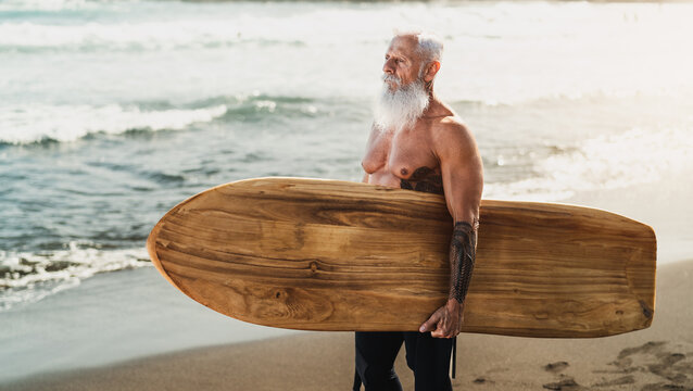 Senior fit man surfing on tropical beach - Elderly healthy people lifestyle and extreme sport concept
