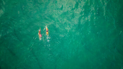 Top drone view ,Two female swimmers swim in the open sea