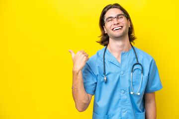 Young surgeon caucasian man isolated on yellow background pointing to the side to present a product