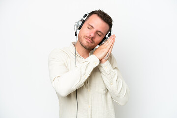 Telemarketer caucasian man working with a headset isolated on white background making sleep gesture...