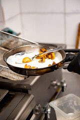 chef hand cooking sauce with mushroom sliced in pan at a restaurant kitchen