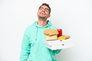Young caucasian man holding fast food isolated on white background laughing