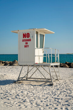Small white lifeguard tower on a beach shore with rocks near the water at Destin, Florida