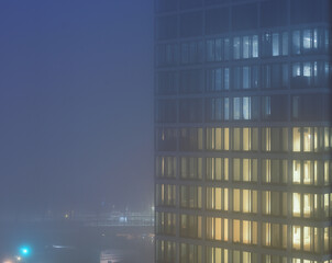 Fototapeta premium illuminated office tower on a foggy night.
