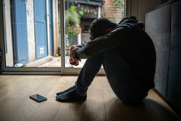 Depressed man. Sad unhappy Man sitting on the floor and holding his head between his legs