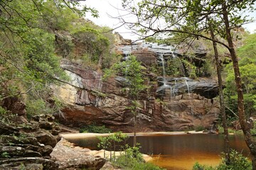 Fototapeta premium Wild nature with trees and small lake. Tree and vegetation. Waterfall through rocks in the middle of the forest in Minas Gerais.