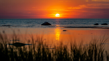 Beautiful view of orange sunset seascape with boulder. Ruhnu, Estonia. Tropical colorful sea...