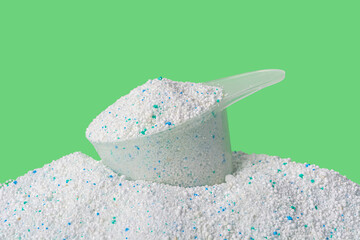 washing powder and a plastic spoon on a green background