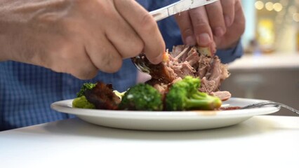 Hands of an elderly man eating a pork knuckle on the bone