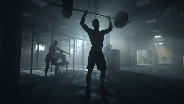 silhouette of weightlifter in gym, brawny man is lifting barbell, deadlift workout in fitness club