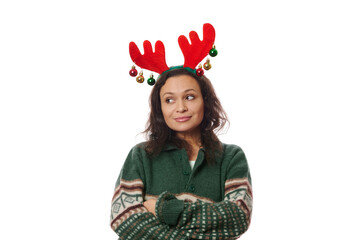 Latin American pretty woman in green sweater and deer antler hoop, thoughtfully looking aside at copy space on white background, posing with her arms crossed. Free space for your advertising text