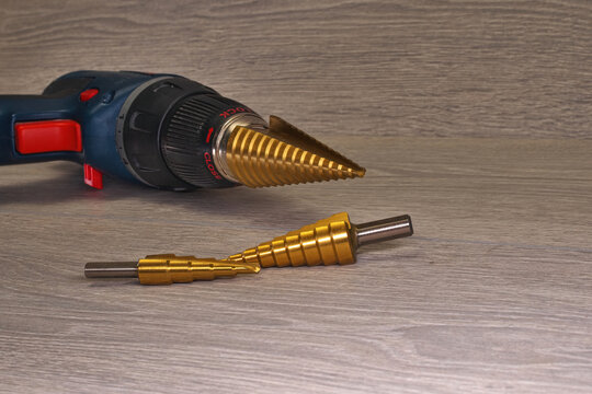 hss step bits. Step drills with a cordless drill on a smoky background. Blurred background. Selective sharpness.