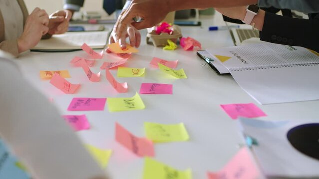 Business meeting, hands planning and sticky notes of creative collaboration and teamwork strategy. Marketing schedule plan, design and working team together in office with stationary and moodboard