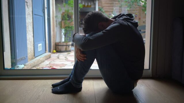 Depressed man. Sad unhappy Man sitting on the floor and holding his head between his legs