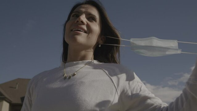 Slow motion low angle close up of smiling woman removing protective mask / Lehi, Utah, United States