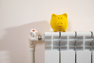 Yellow piggy bank on the heating radiator.