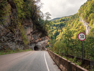 Mountain highway, at the entrance to the tunnel cut into the rock. Beautiful street in a rocky...