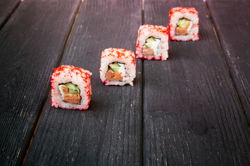 Female hand takes california sushi rolls with Chinese chopsticks. Selective focus, black background
