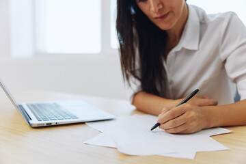 A woman works and learns by writing down text on paper with a pen and checking for errors, studying and teaching in college, business work