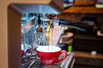 Barista przygotowuje kawę, używając profesjonalnego ekspresu do kawy, zbliżenie na filiżankę
