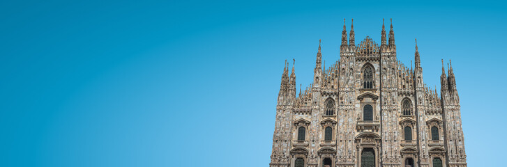 Fototapeta na wymiar Banner with magnificent Cathedral of Milano at blue sky gradient background with copy space, Milan, Italy. Concept of historical and religious heritage sites conservation