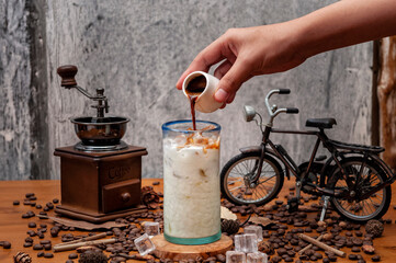 Barista przygotowuje mrożone cappuccino, wlewając espresso do szklanki - obrazy, fototapety, plakaty