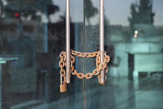 There is a lock on the office door. Rusty chain on glass door and lock on it, bankrupt or closed business concept