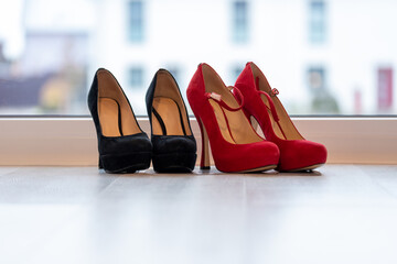 Red and Black high heel pumps in front of a window and on a light floor