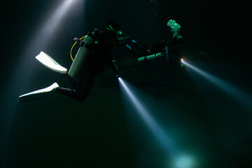 cave diver instructor leading a group of divers in a mexican cenote underwater