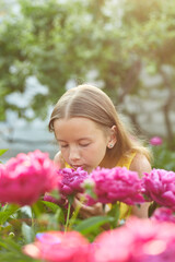 Happy little girl with braces in the garden in bushes of peonies
