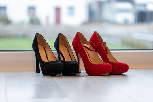 Red and Black high heel pumps in front of a window and on a light floor