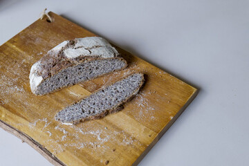 Freshly cut homemade rye bread on wooden cutting board on kitchen table