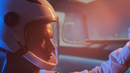 A woman astronaut in a space suit aboard the orbital station. A young female cosmonaut pilots a spaceship. Galactic travel and science concept. © Acronym