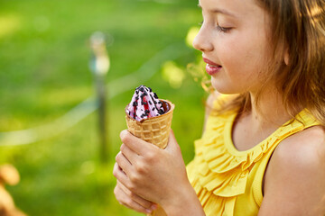 Happy girl with braces eating italian ice cream cone smiling while resting in park on summer day