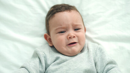 Adorable hispanic baby lying on bed crying at bedroom