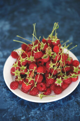 Fresh raspberries with tails on a white plate. Close-up.