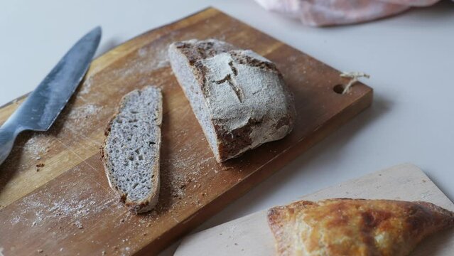 Freshly cut dark rye bread on wooden cutting board on breakfast table