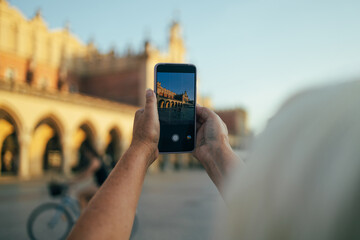 A hand taking photo of Sukiennice with smartphone, Krakow, Poland