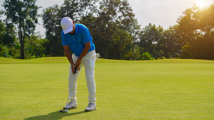 Golfer putting ball on the green golf, lens flare on sun set evening time.