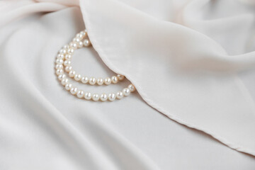 Pearls necklace on creme off-white silky background