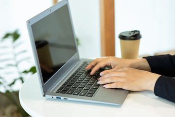 Young Asian woman using a laptop computer sitting in a cafe.