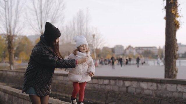 Happy family, young mother and daughter are walking in the autumn park. Mothers Day. Slow motion